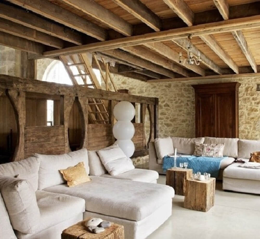 Rustikales Wohnzimmer mit freiliegenden Holzbalken und einem großen weißen Sofa über Decorilla