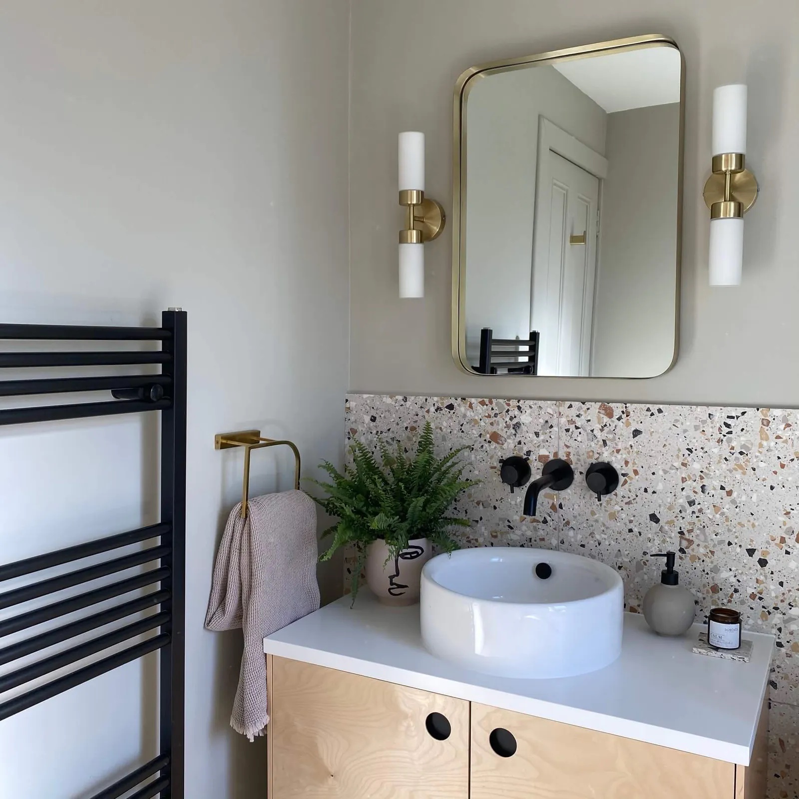 Bathroom with a brass mirror and walls painted in Lick Greige 01 