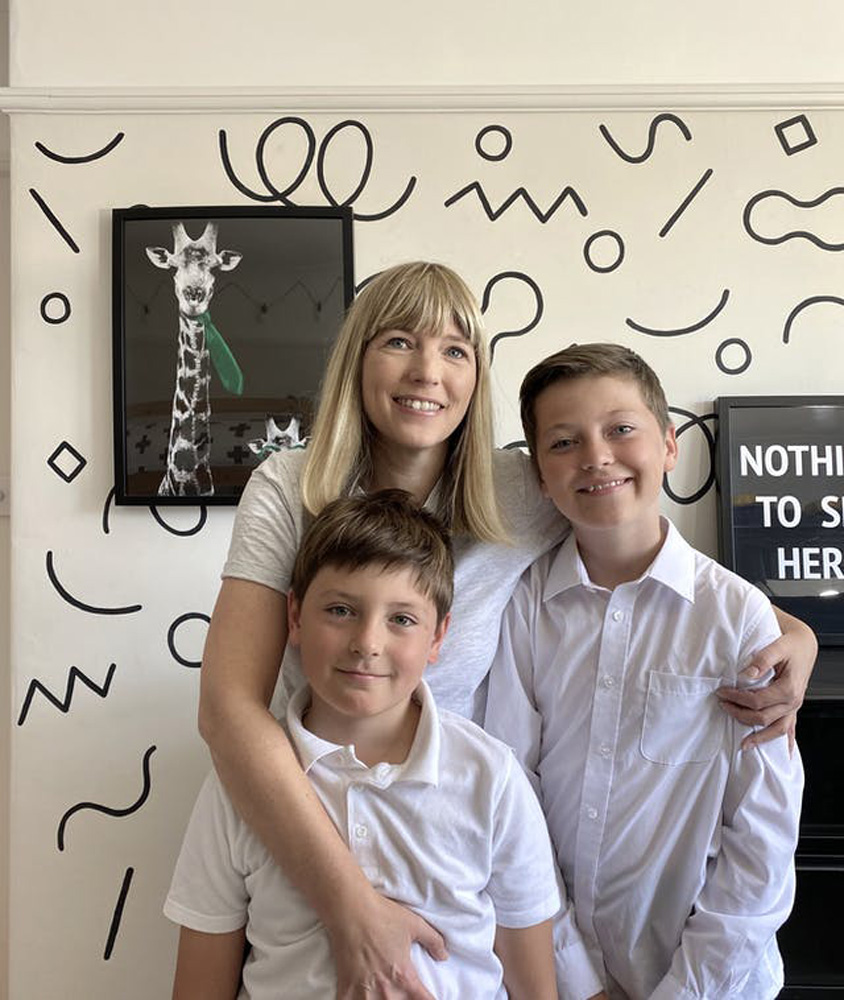 Blonde woman with two kids in front of a geometric pattern wall