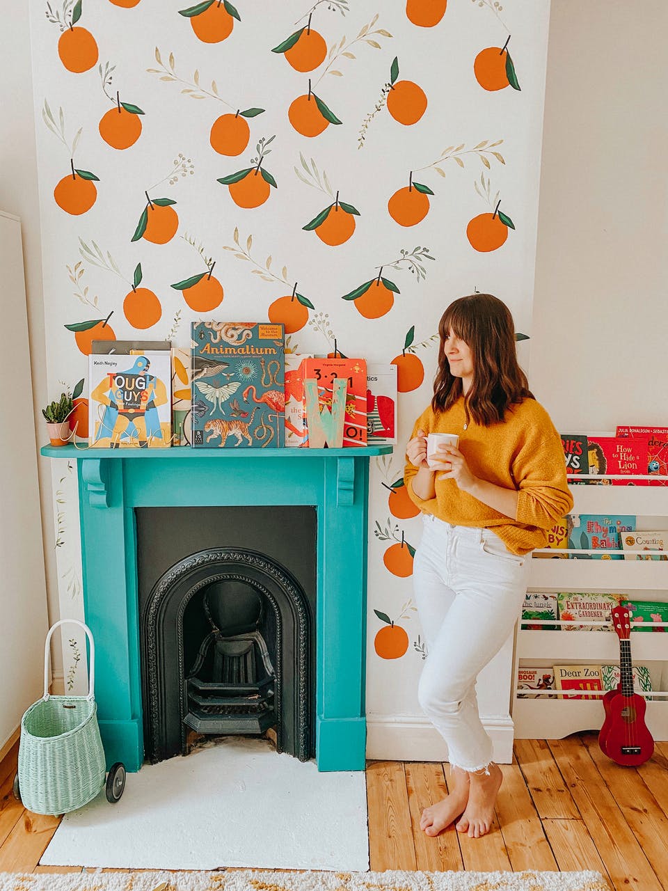 Jess von @charminglifebyjess steht vor ihrem blauen Kamin und dem Schornstein mit Orangenwandbild