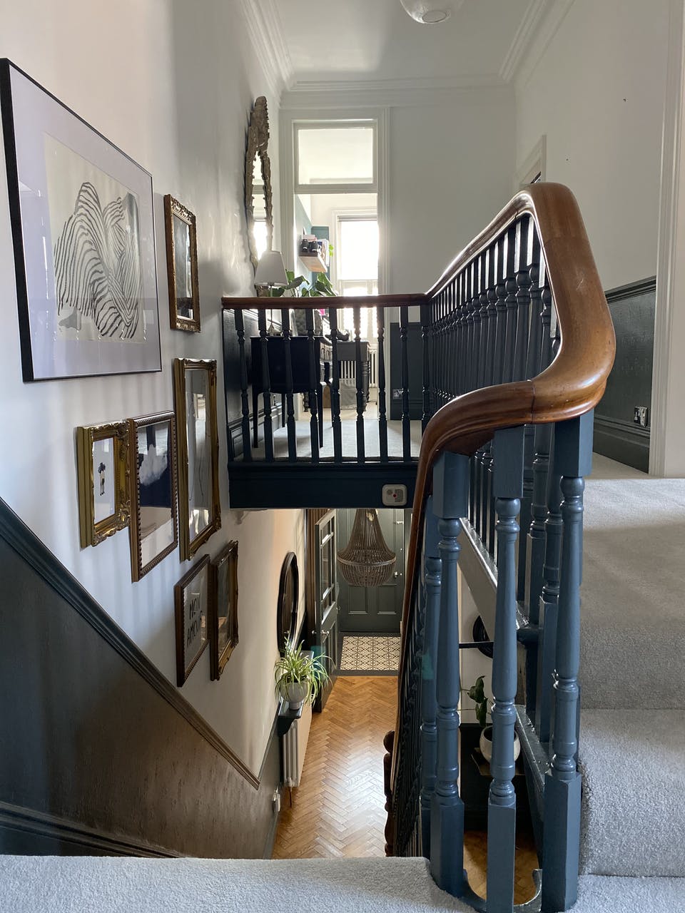 Black staircase with wood finish bannister and panelled gallery wall
