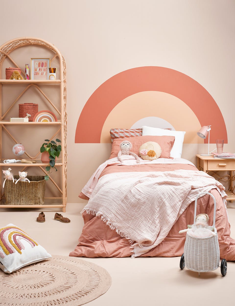 Kids bedroom DIY pastel pink rainbow mural behind bed 