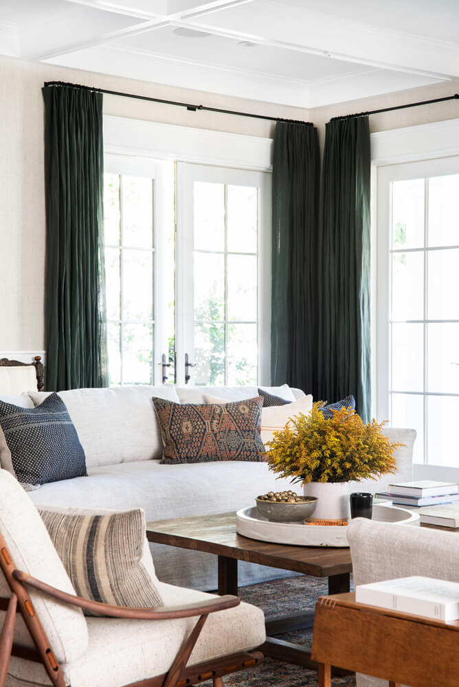 Modern farmhouse living room with green curtains and flowers via Amber Interior Design