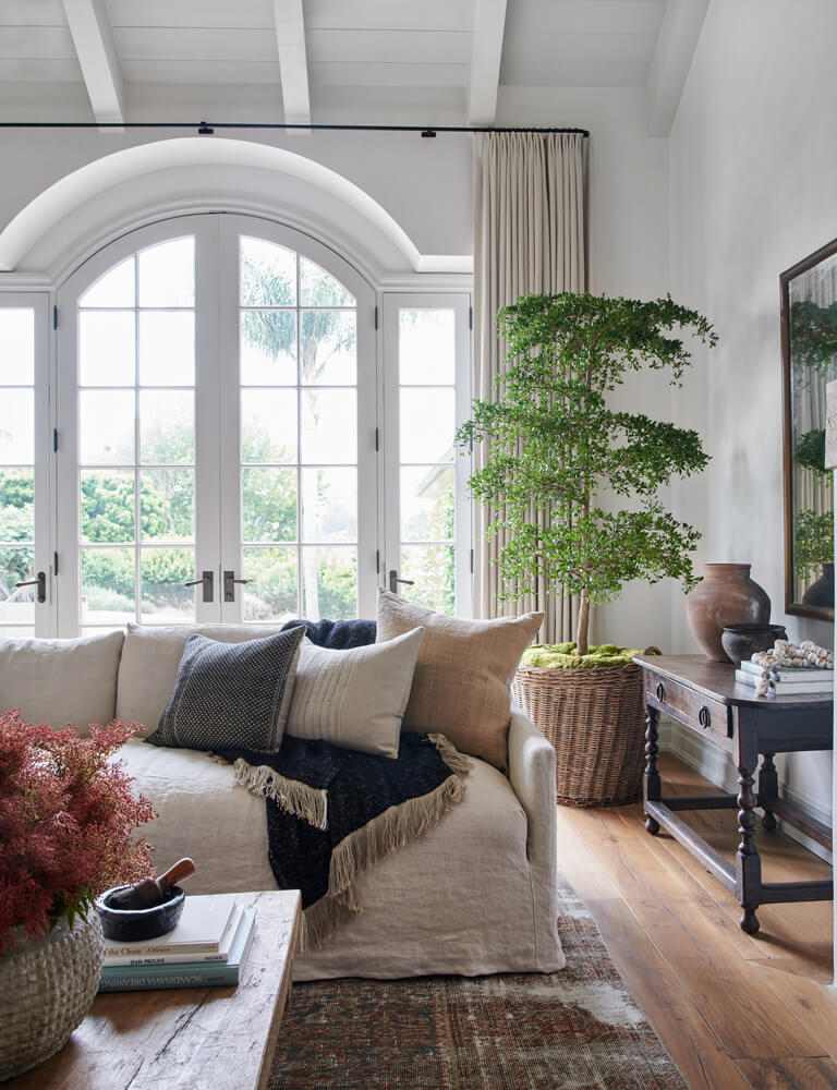 Modern farmhouse living room with a large window and potted plant via Amber Interior Design