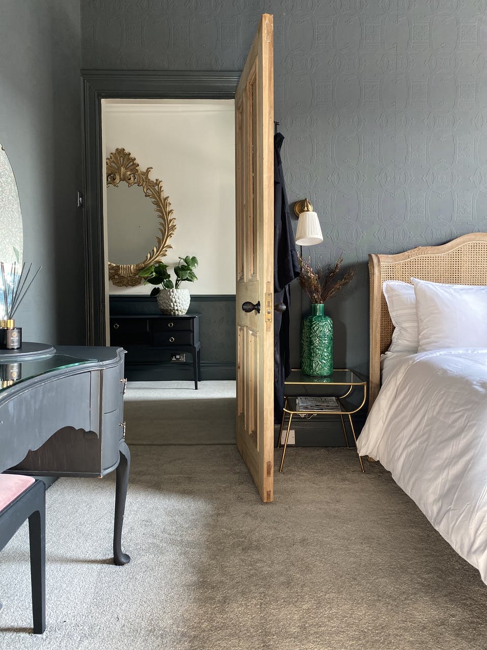 Bedroom painted in black with light wooden finishes leading to the hallway with black panelling