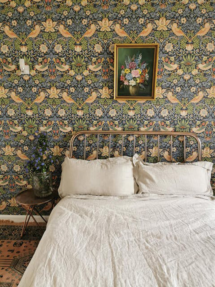 Cottage bedroom with green floral wallpaper and raw linen sheets