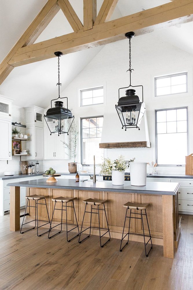 Moderne Landhausküche mit einer überdimensionalen Kücheninsel und schwarzen Pendelleuchten über Studio McGee