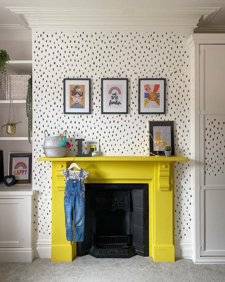 Sunshine yellow fireplace with black and white tiny polka dot wallpaper on chimney breast
