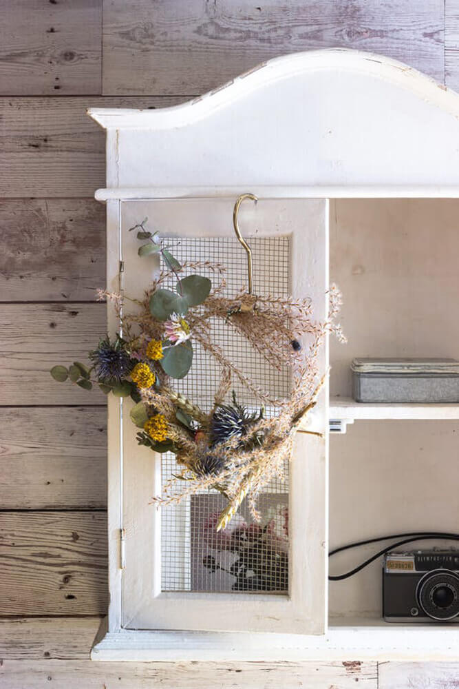 Handmade wreath hanging on white cabinet