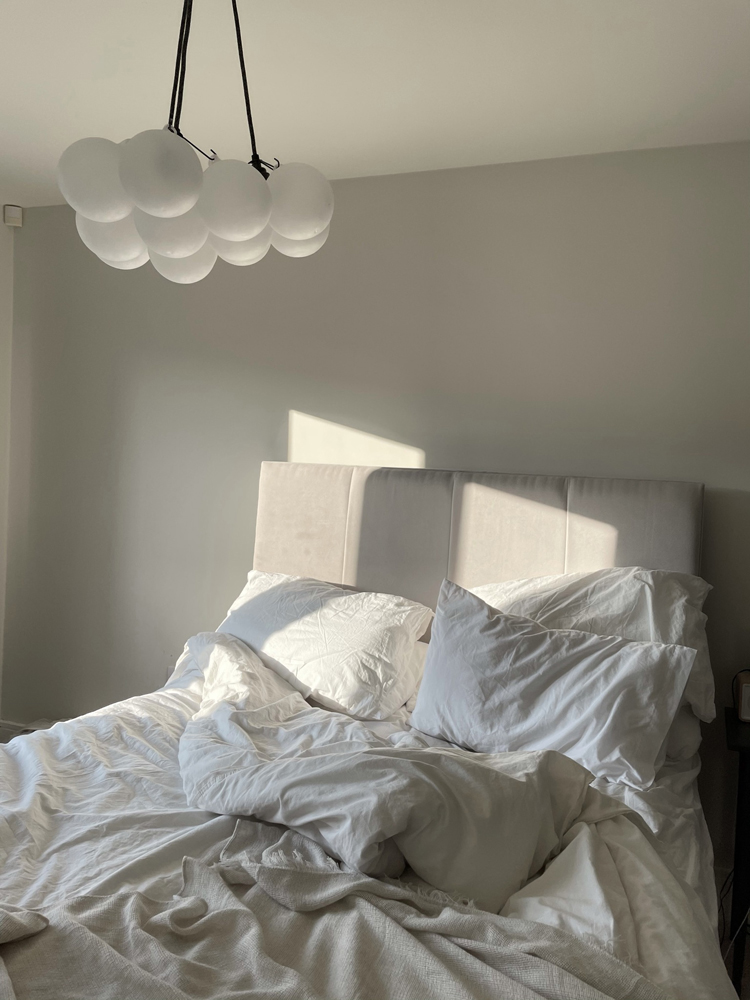 Unmade bed with wall painted in Lick White 03