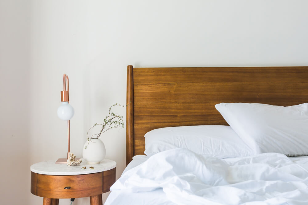 Unmade bed with lamp and side table 