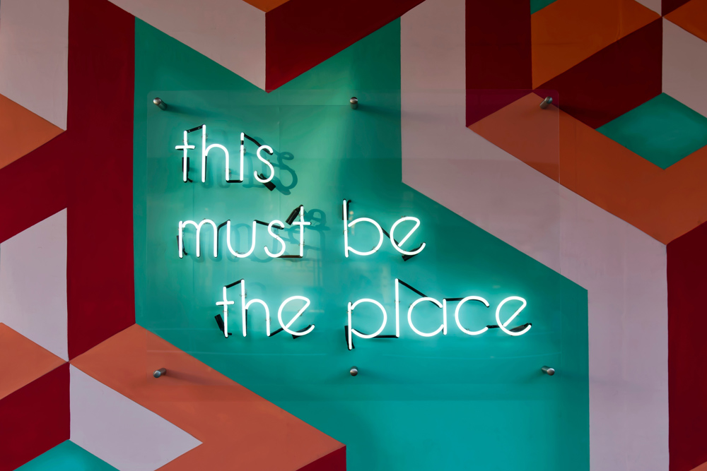 Lick home interior inspiration Miami art deco style neon sign that says 'this must be the place'