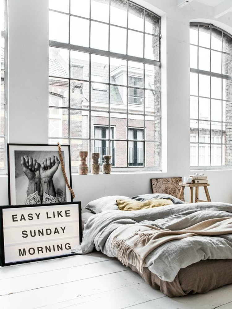 Unmade bed with large windows