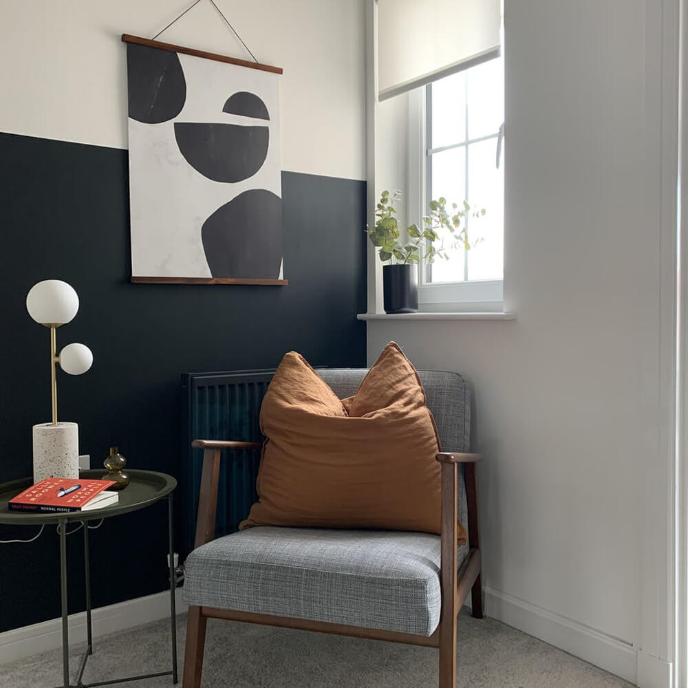 Wall half painted in Blue 07, behind a lounge chair with an orange pillow
