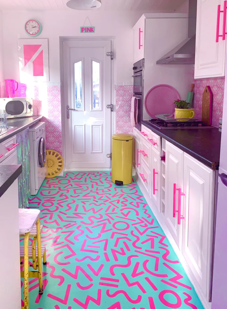 Maximalist kitchen decorated in bright pink with teal flooring