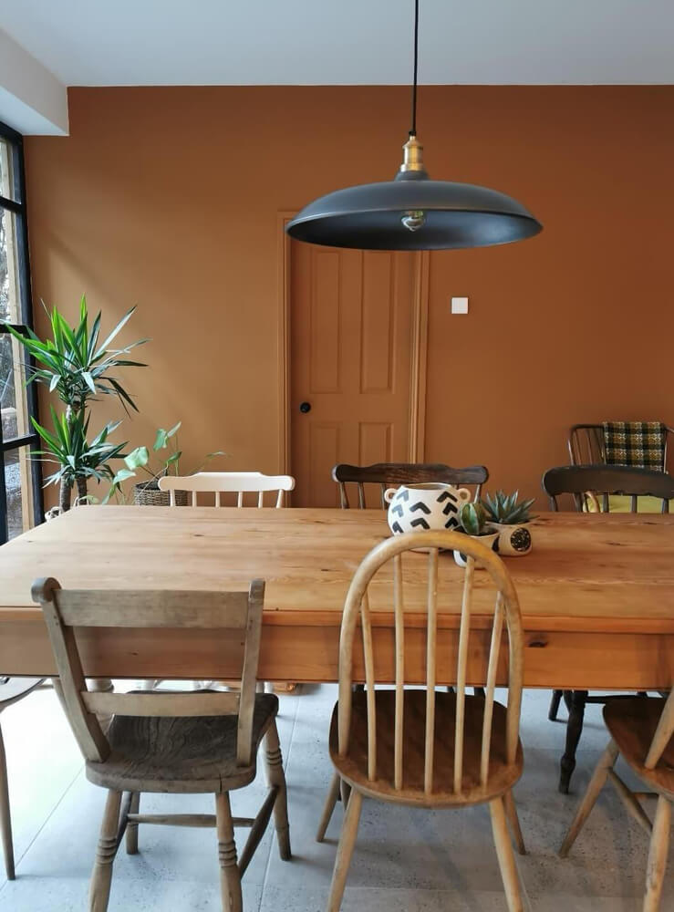 Dining room with wooden table and chairs with orange painted walls