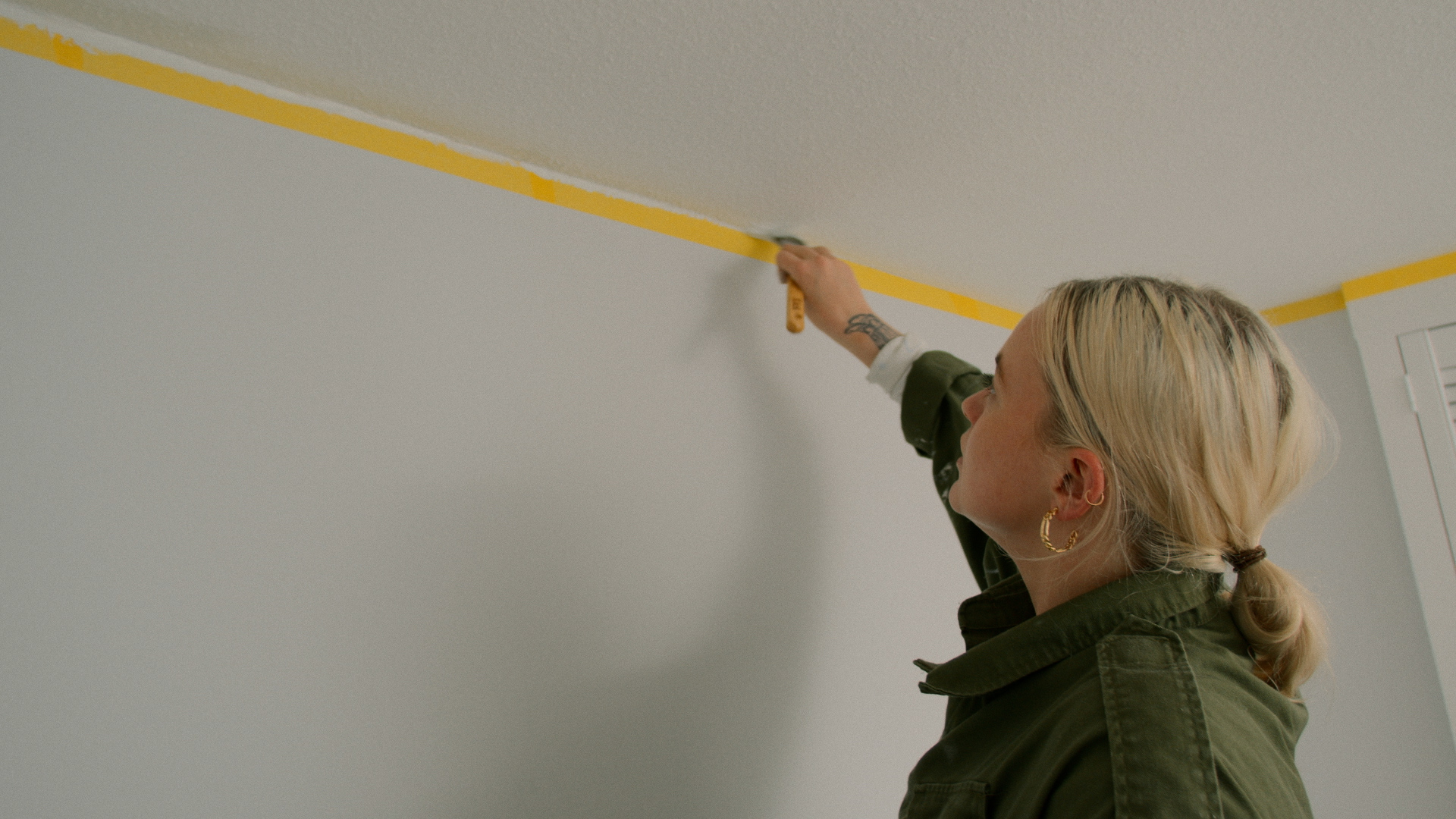 Woman painting a ceiling over masking tape