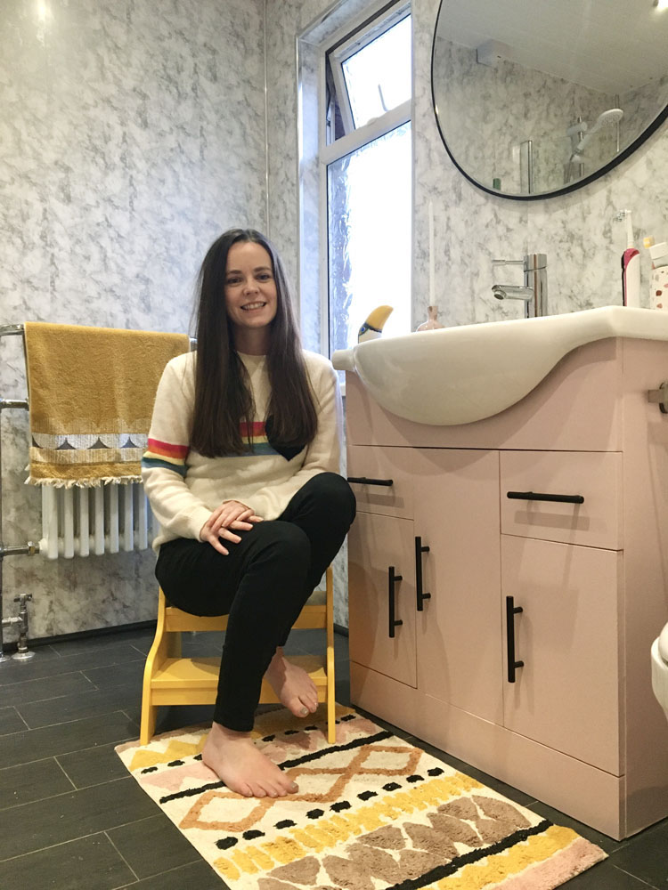 A photo of of Sarah (@the_joys_at_no44) sitting in front of her bathroom sink and cabinets decorated in Lick Pink 03