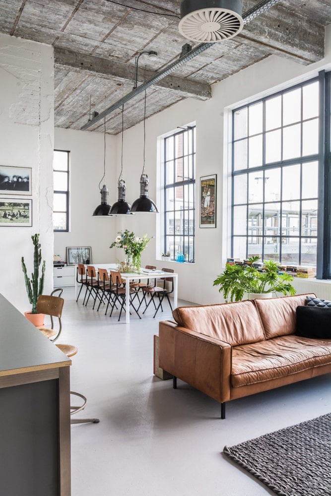 Open-Plan industrial loft space with white-painted walls and brown furniture via Everythingelze