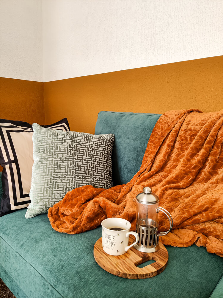 Orange living room. with green couch with black and white cushions