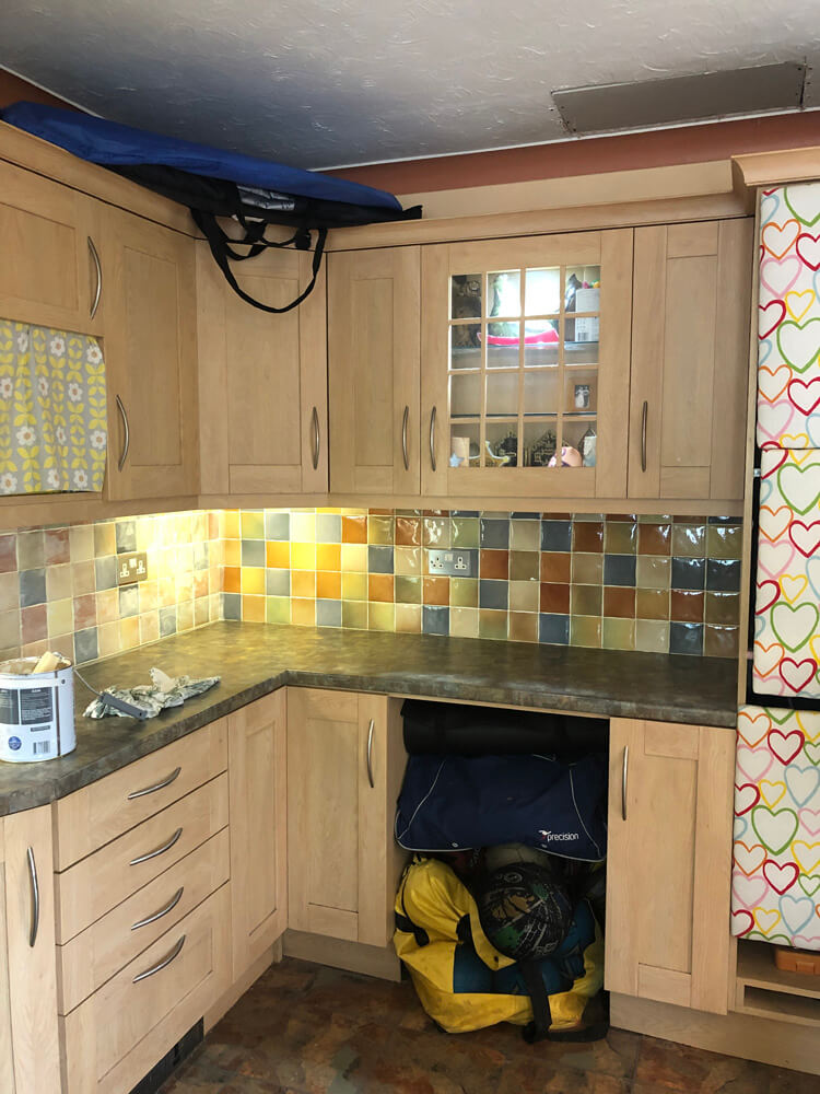 Dated kitchen with wooden cabinets and a tiled splashback