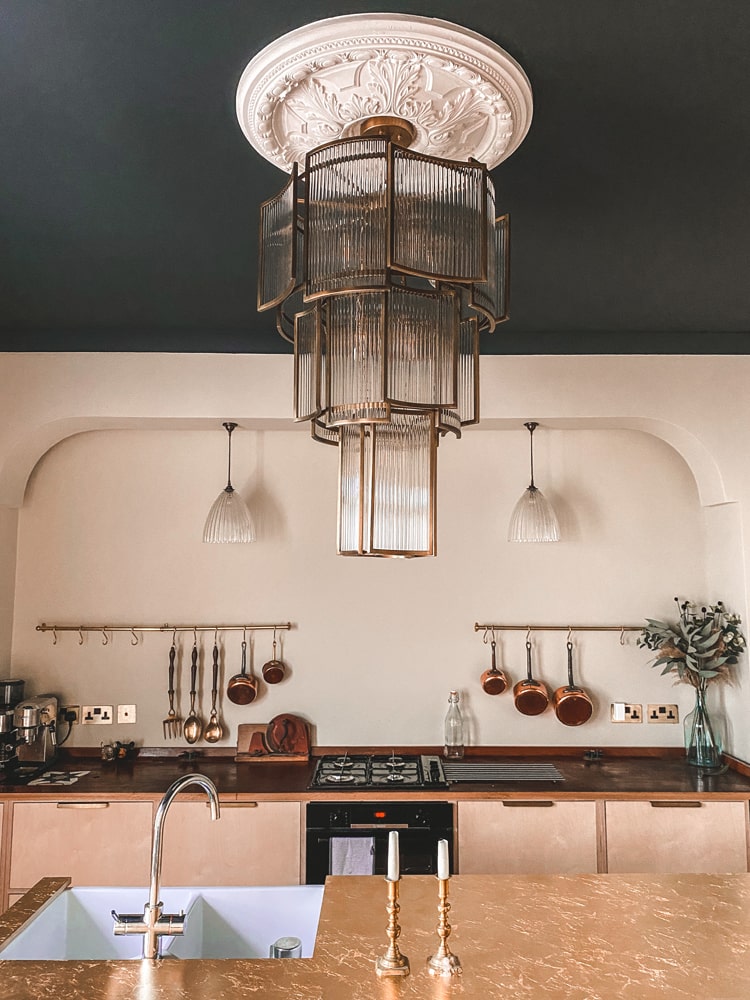Large pendant lighting hanging over industrial kitchen with rose gold counter tops 