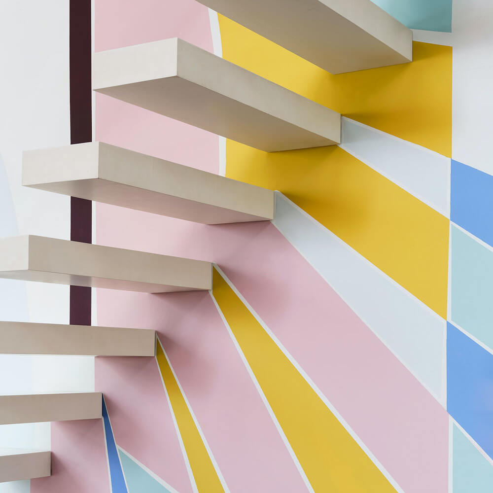Wall mural with geometric striped shapes painted in Lick pastel paint colours