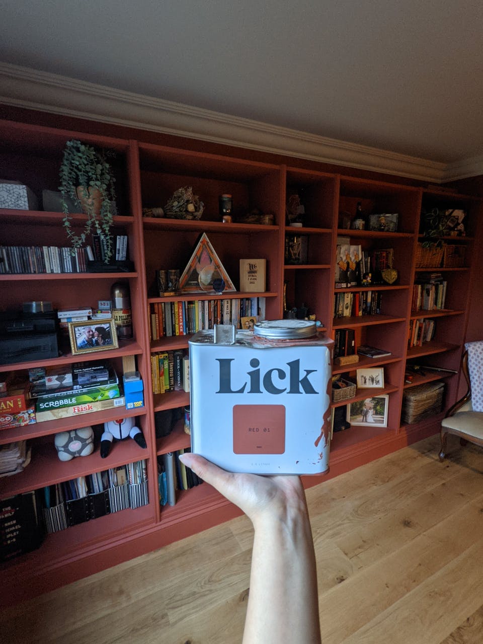 Billy-Bücherregal gestrichen in Lick-Farbe Red 01 mit Hand, die die Dose hochhält